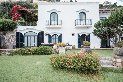 uma mulher sentada num banco em frente a uma casa branca em Villa Michika by Elite Villas em Capri