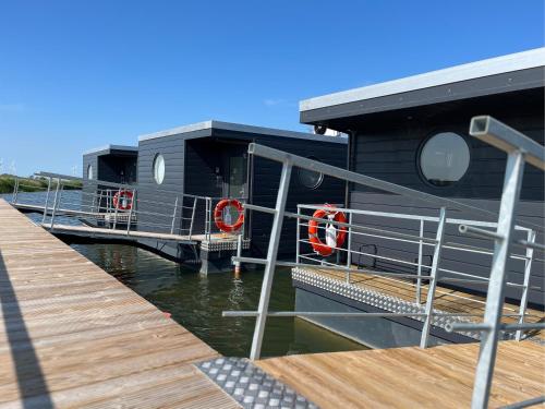 ein Haus am Wasser neben einem Dock in der Unterkunft Hausboot - Nordsonne 11 in Wangerland