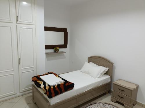 a small bedroom with a bed and a dresser at IMMEUBLE BRINI in Kairouan
