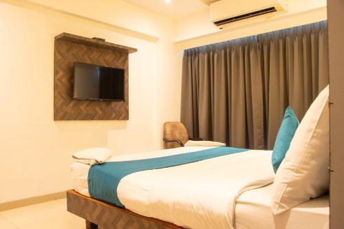 a bedroom with a bed and a tv on the wall at J R Residency in Navi Mumbai