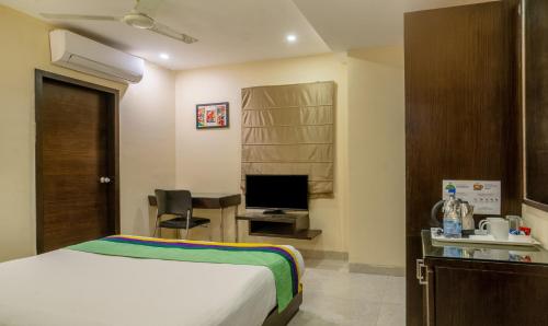 a bedroom with a bed and a desk with a television at Treebo Acsys, Gachibowli in Hyderabad