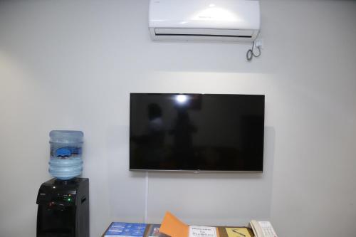 uma televisão de ecrã plano numa parede com uma garrafa de água em Trivelles Executive Suites Islamabad em Islamabad