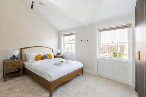 a white bedroom with a bed and two windows at Luxurious Central 4BR Mansion 2 min from Hyde Park in London