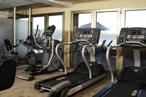 a gym with treadmills and ellipticals and windows at El Casco Art Hotel in San Carlos de Bariloche