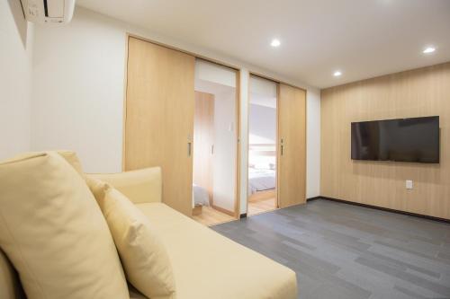 a living room with a white couch and a television at 1min walk to Higashi Shinjuku sta 8PPL Shinjuku Gyoen丶 National Garden丶 Kabukicho丶 Shinjuku Station丶 Golden Gai丶 Tokyo Metropolitan Government Building YYoQB in Tokyo