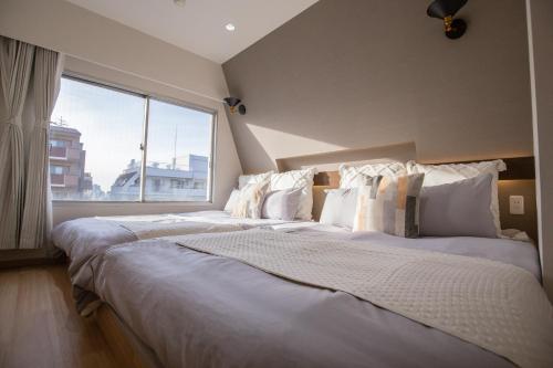 two beds in a room with a large window at 1min walk to Higashi Shinjuku sta 8PPL Shinjuku Gyoen丶 National Garden丶 Kabukicho丶 Shinjuku Station丶 Golden Gai丶 Tokyo Metropolitan Government Building YYoQB in Tokyo
