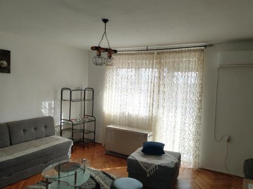 sala de estar con sofá y ventana en Apartman Petra en Leskovac
