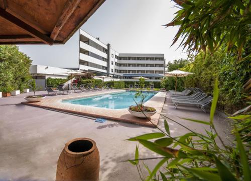 a swimming pool with chairs and a building in the background at Hotel Enterprise in Montalto di Castro