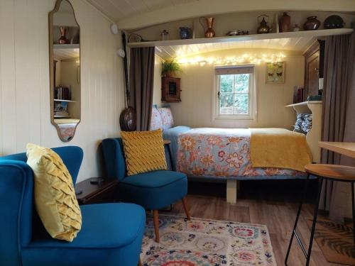 a bedroom with a bed and two blue chairs at The Humble Hut in Wooler