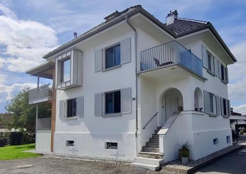 ein weißes Haus mit einer Veranda und einer Treppe in der Unterkunft Haus Olga in Hörbranz