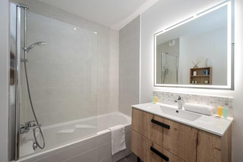 une salle de bain avec un lavabo, une baignoire et un miroir dans l'établissement C035-Cannes Centre appartement 3 pièces avec parking, à Cannes