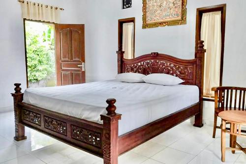 een slaapkamer met een bed met een houten frame bij Tebluess Guesthouse Gianyar RedPartner in Bedahulu