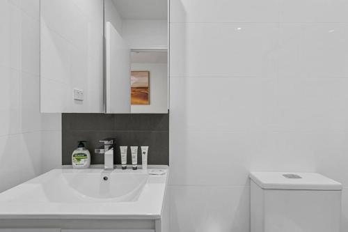 a white bathroom with a sink and a mirror at Modern Studio Retreat in Crown St with AirCon in Sydney