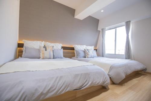 two beds sitting next to each other in a bedroom at 1min walk to Higashi Shinjuku sta 8PPL Shinjuku Gyoen丶 National Garden丶 Kabukicho丶 Shinjuku Station丶 Golden Gai丶 Tokyo Metropolitan Government Building YYoQA in Tokyo