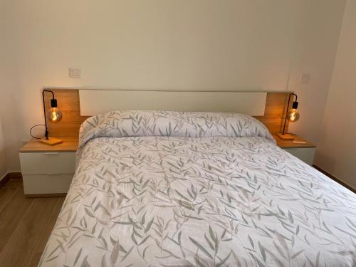 ein Bett in einem Schlafzimmer mit zwei Nachttischen und zwei Lampen in der Unterkunft Be Room Oasis Harmony in Maspalomas