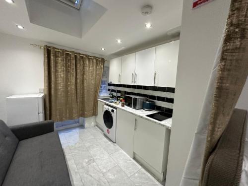 cocina con armarios blancos, lavadora y secadora en Beautiful Double Room with Free Wi-Fi and free parking en Lewisham