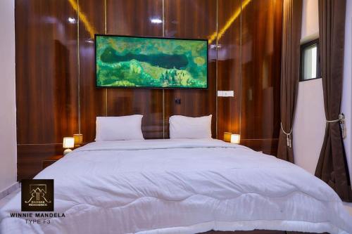 ein Schlafzimmer mit einem großen Bett und einem Gemälde an der Wand in der Unterkunft Appart Winnie/ Ramses in Cotonou