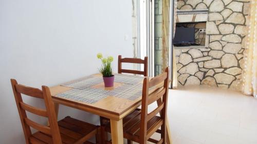 una mesa de madera con sillas y una planta. en Guest House Suga 1, en Qeparo
