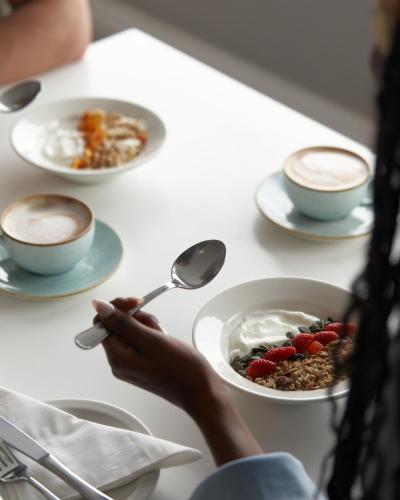 开普敦The Bantry Aparthotel by Totalstay的一个人手里拿着一碗麦片和几杯咖啡。