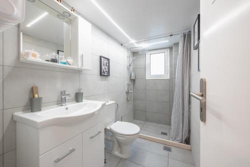La salle de bains blanche est pourvue d'un lavabo et de toilettes. dans l'établissement Golden Comfort By Greece Apartments, à Athènes