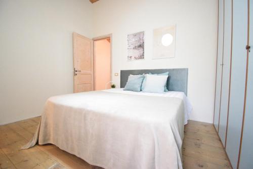a white bedroom with a large white bed with blue pillows at La Casa nel Borgo in San Pietro in Casale