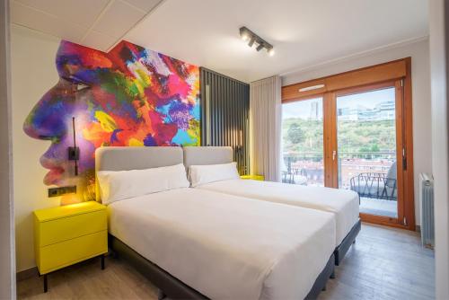 1 dormitorio con 1 cama con una pintura en la pared en Bilbao Apartamentos Atxuri, en Bilbao