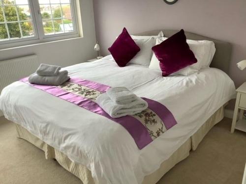塞爾西的住宿－Caedwalla House, Selsey，一间卧室配有一张大床,提供紫色和白色枕头