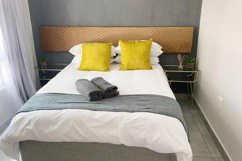 een bed met gele kussens en 2 handdoeken erop bij Gorgeous 2-Bedroom apartment in Secunda