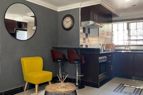 een keuken met een gele stoel en een klok aan de muur bij Gorgeous 2-Bedroom apartment in Secunda