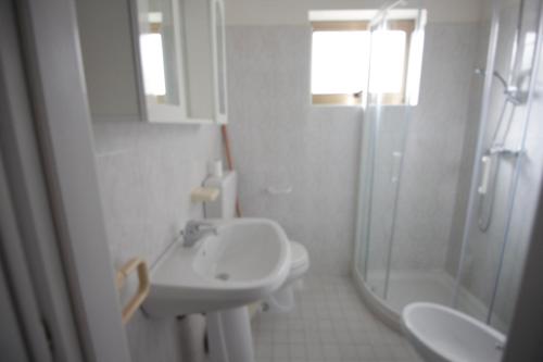 ein weißes Bad mit einem Waschbecken und einer Dusche in der Unterkunft Villa Ketty Trilocale in San Michele al Tagliamento