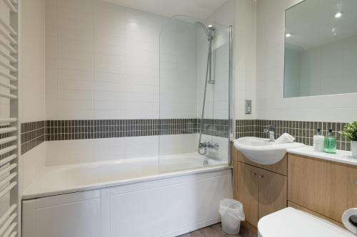 a white bathroom with a tub and a sink at Modern 2 bed in central MK, Free Parking, Smart TV in Buckinghamshire