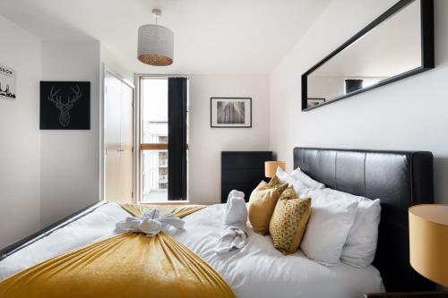 a bedroom with a bed with white sheets and gold pillows at Modern 2 bed in central MK, Free Parking, Smart TV in Buckinghamshire