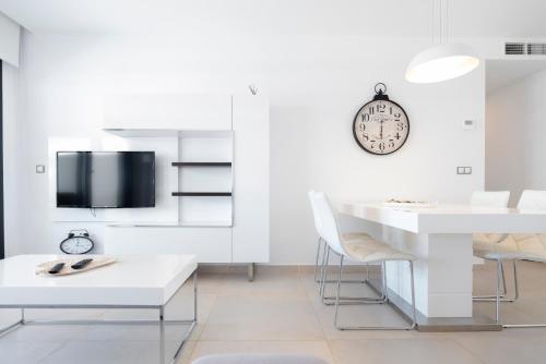 a living room with a white table and chairs and a clock at Infinity View - Access to hot tubs & pools in Arenales del Sol