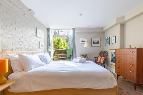 a bedroom with a white bed and a brick wall at Rustic Modern 1BD Flat wGarden Stoke Newington! in London
