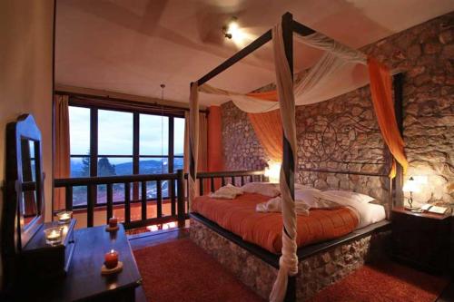 a bedroom with a canopy bed and a balcony at Αέσκω in Vitina