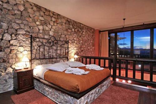 a bedroom with a bed with a stone wall at Αέσκω in Vytina