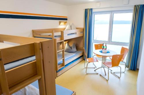 ein kleines Zimmer mit Etagenbetten sowie einem Tisch und Stühlen in der Unterkunft Jugendherberge Ratzeburg am See in Ratzeburg