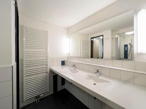 uma casa de banho com 2 lavatórios e um espelho em Jugendherberge Ratzeburg am See em Ratzeburg