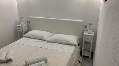 ein weißes Schlafzimmer mit einem Bett mit zwei Nachttischen in der Unterkunft Villino Mimosa in Costa Rei