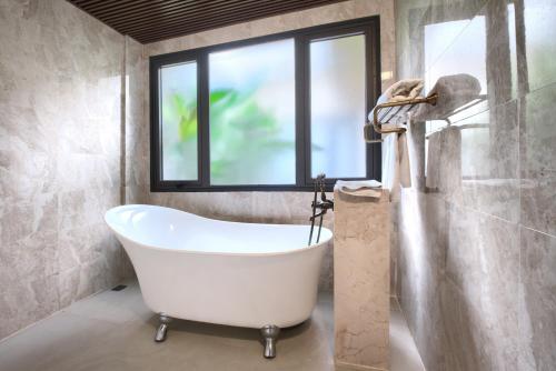 a bath tub in a bathroom with a window at THE BLOSSOM RESORT ISLAND - All Inclusive in Da Nang