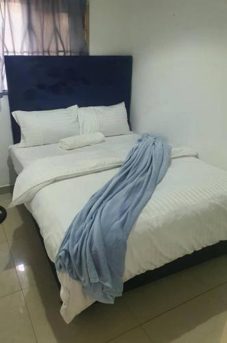 Bett mit blauem Kopfteil sowie weißer Bettwäsche und Kissen in der Unterkunft BlueView Apartments in Kitwe