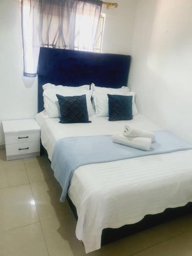 2 Betten mit weißer Bettwäsche und blauen Kopfteilen in einem Zimmer in der Unterkunft BlueView Apartments in Kitwe