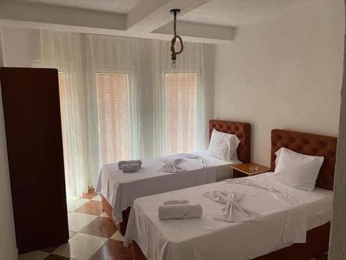 a bedroom with two beds with white sheets and windows at Hotel Montenegro in Struga