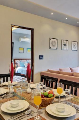 Una mesa de comedor con un bol de fruta y copas de vino. en ELIVAAS Radhyam Luxe 2BHK Villa with Pvt Pool, en Udaipur