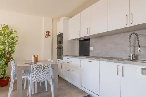 une cuisine avec des armoires blanches et une table et des chaises dans l'établissement 3-Br Apartment Terrace steps from Beaches, à Cannes
