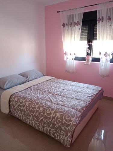Bett in einem Schlafzimmer mit rosa Wänden und Fenstern in der Unterkunft Apartman SARA in Vršac