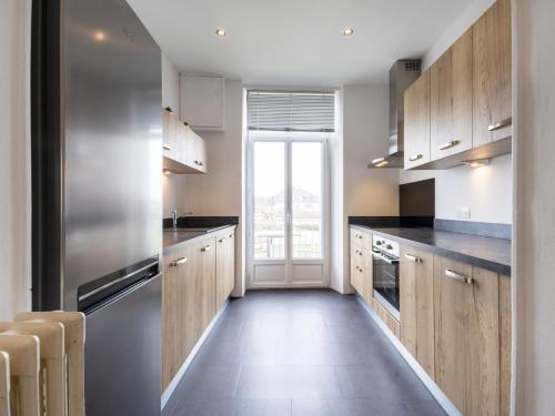 une cuisine avec des placards en bois et une grande fenêtre dans l'établissement Residence Louis Quartier Centre Ville, à Vittel