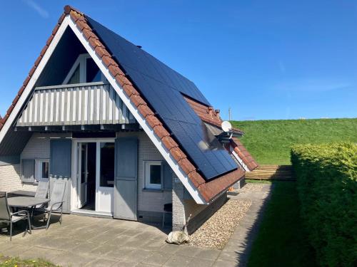 a house with a pitched roof with a patio at am Deich 6 pers House with a private terrace behind a dike by the Lauwersmeer in Anjum