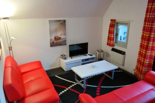 AnjumにあるNatascha 6pers House Near Lauwersmeer National Parkのリビングルーム(赤い椅子、テーブル付)