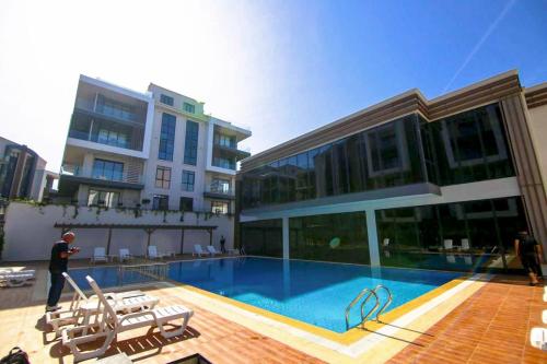 un hombre parado frente a un edificio con piscina en Luxury Duplex With Wonderful View In Izmit, en Çavuşçiftliği